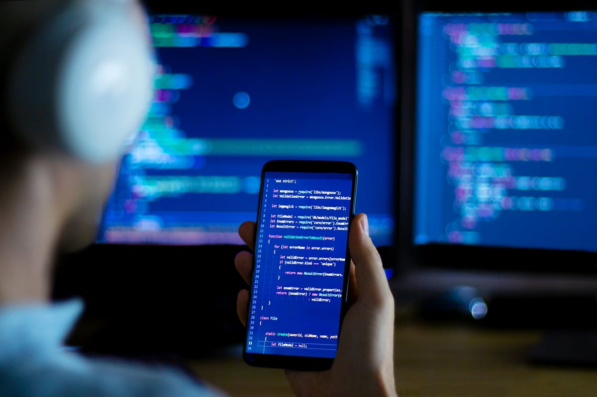 Software developer freelancer with white headphones and glasses working with program code